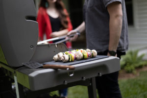 man and woman grilling kabobs in the back yard