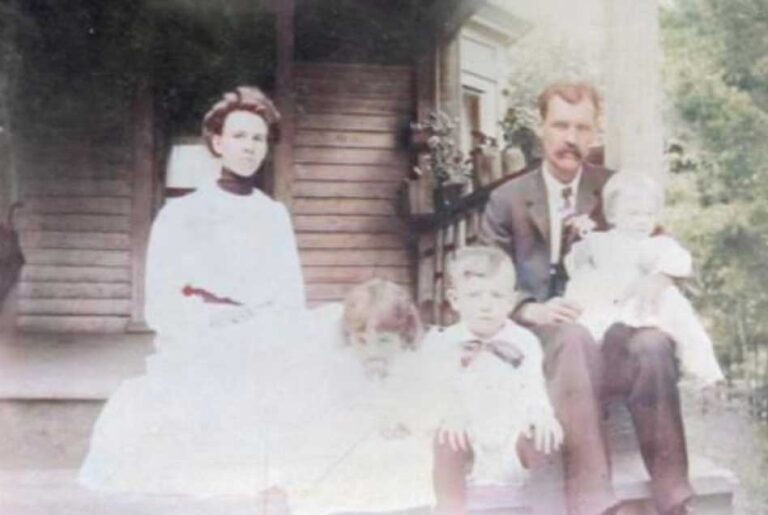 Early photograph of a family on the porch of the house