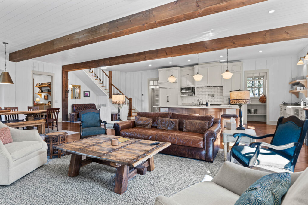 Open great room with leather sofas, timber beams and the kitchen beyond