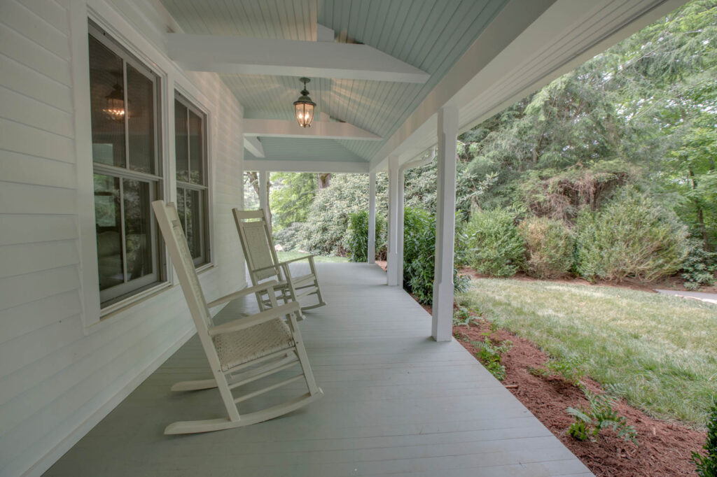 Wraparound porch with white rocking chairs
